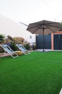 a lawn with two chairs and an umbrella at Villa Tauria- Casa de campo em aldeia medieval in Sabugal