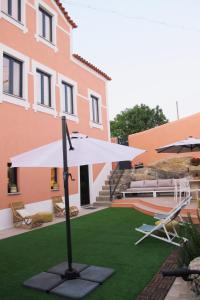a white umbrella on a lawn in front of a building at Villa Tauria- Casa de campo em aldeia medieval in Sabugal