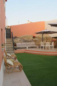 a patio with chairs and an umbrella and grass at Villa Tauria- Casa de campo em aldeia medieval in Sabugal