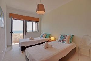 two beds in a room with a view of the ocean at Quarteira Beach & Ocean View by Homing in Quarteira