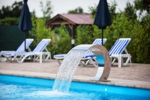 a water fountain in a pool with chairs and umbrellas at Аквамарин in Gribovka +51 photos