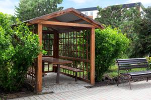 a wooden gazebo with a picnic table and a bench at Аквамарин in Gribovka