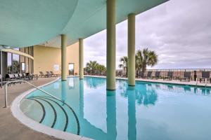 a large swimming pool with chairs and a building at Dauphin Island Condo with Pool, Balcony and Ocean View in Dauphin Island