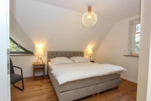 una camera da letto con un letto con lenzuola bianche e una finestra di Schilfkante - Am Ufer a Wieck