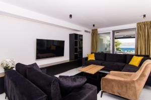 uma sala de estar com um sofá preto e almofadas amarelas em Mia em Trogir