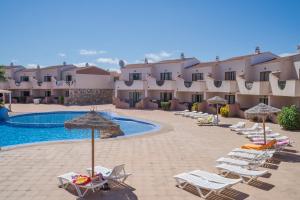 Un grupo de sillas y sombrillas junto a una piscina. en Apartamentos Moon Dreams Los Lentiscos, en Cala en Blanes 37 fotos más
