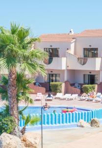 Un complejo con una palmera y una piscina. en Apartamentos Moon Dreams Los Lentiscos, en Cala en Blanes