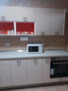 a kitchen with white cabinets and a microwave on a counter at Apartament Nicoleta in Jurilovca