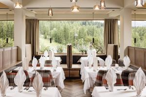 a restaurant with white tables and chairs and large windows at Sporthotel Obereggen in Obereggen