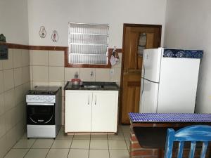 een keuken met een witte koelkast en een wastafel bij Casa quadra praia Jacaraipe in Serra