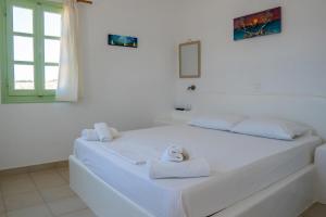 a white bedroom with a bed with towels on it at Sunset Studios & Rooms in Antiparos