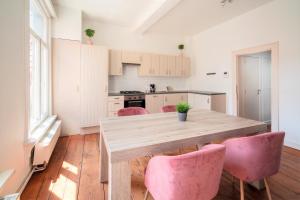 een keuken met een houten tafel en roze stoelen bij Antwerp Old Town Apartment in Antwerpen