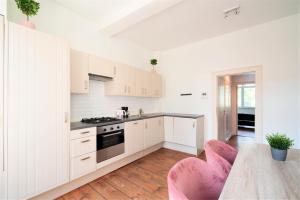 a kitchen with white cabinets and pink chairs at Antwerp Old Town Centrum Apartment in Antwerp