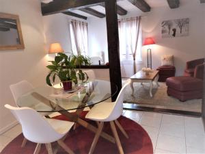 una sala da pranzo con un tavolo di vetro e sedie bianche di Gites Aux Fines Bulles d'Alsace SPA privatif en supplément a Bergheim