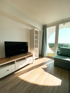 ein Wohnzimmer mit einem Flachbild-TV und einem Sofa in der Unterkunft Marine Apartman By BLTN Siófok in Siófok