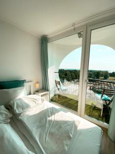 Schlafzimmer mit einem Bett und Blick auf einen Balkon in der Unterkunft Marine Apartman By BLTN Siófok in Siófok
