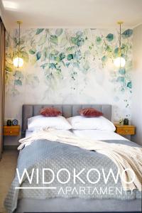 a bedroom with a bed with a floral mural on the wall at WIDOKOWO Apartamenty in Ełk