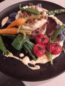 a black plate of food with vegetables on it at Hôtel-Restaurant Le Lion d'Or in Porrentruy