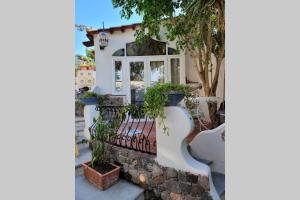 a white house with a bench and a tree at Arabesque in Lacco Ameno