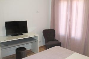 ein Wohnzimmer mit einem TV und einem Stuhl in der Unterkunft Girassol Alojamento Local in Montemor-o-Novo