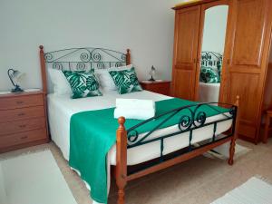 Un dormitorio con una cama con una manta verde y un espejo. en Casa da Sao, en Nazaré