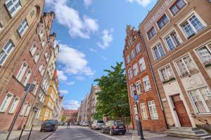 una calle de la ciudad con edificios y coches aparcados en la calle en Apartament Attyka Old Town Gdańsk en Gdansk
