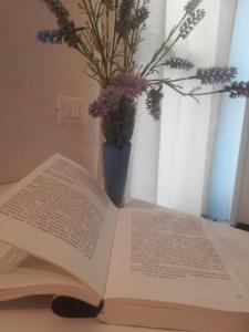 an open book on a table with a vase of flowers at Camera romantica nel carugio in Riomaggiore