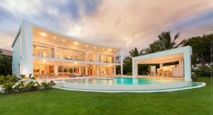 a large house with a swimming pool in the yard at Luxury 5-room modern villa with movie theater at exclusive Punta Cana golf and beach resort in Punta Cana