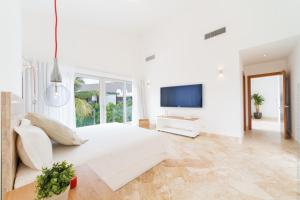 ein weißes Schlafzimmer mit einem großen Bett und einem TV in der Unterkunft Luxury 5-room modern villa with movie theater at exclusive Punta Cana golf and beach resort in Punta Cana