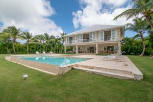 a large house with a swimming pool in front of it at Golf-front villa with large spaces, staff and pool, situated in luxury beach resort in Punta Cana