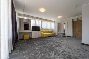 ein Wohnzimmer mit einem gelben Sofa und einem Fernseher in der Unterkunft Hotel Caesar 2 in Kardschali