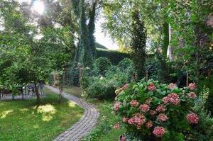 a path in a garden with pink flowers and trees at Tresor Barska Apartments in Krakow