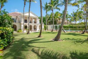 una casa grande con palmeras delante en Luxury golf villa with private pool and service staff in exclusive resort near private beach, en Punta Cana