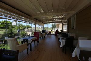 un comedor con mesas, sillas y ventanas en Assortie La Villa Hotel, en Agva