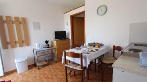 a kitchen with a table with chairs and a clock on the wall at Apartment Klimno 3 in Klimno