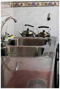 two pots sitting on top of a kitchen sink at El Camino Hostel in Mina Clavero