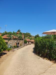 a dirt road leading to a house with an umbrella at El Jiniebro Turismo Rural in Valencia de Alcántara
