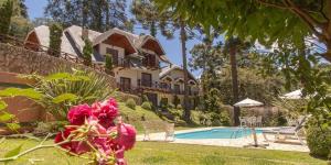 a house with a swimming pool in front of a yard at Pousada D'lines in Campos do Jordão