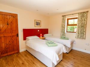 two twin beds in a room with a door at 1 The Stables in Haven Street