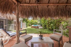 un patio con mesa, sillas y sombrilla de paja en Casa Nona Azul, en Cancún