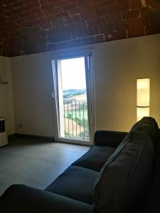 a living room with a couch and a large window at La casa di Isola in Peccioli +24 photos