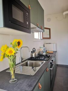 a kitchen with a sink and a vase with yellow flowers at La casa di Isola in Peccioli