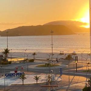 a view of a beach with the sun setting over the water at Casa na orla da Praia do Forte in Cabo Frio