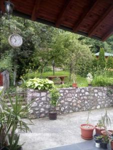 a stone wall with a bench and a clock in a garden at Cumurija Bridge Accommodation in Sarajevo
