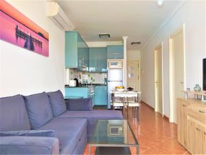 ein Wohnzimmer mit einem lila Sofa und einer Küche in der Unterkunft Yumbo - Apartment in Playa del Ingles