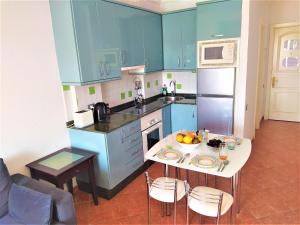 eine Küche mit blauen Schränken und einem Tisch mit Obst darauf in der Unterkunft Yumbo - Apartment in Playa del Ingles + 16 Fotos