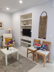 - un salon avec deux chaises et une télévision dans l'établissement Long Beach Apartamento AL, à Praia da Vitória