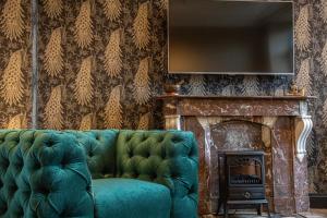 a living room with a green couch and a fireplace at Eigenheimer B&B in Simpelveld
