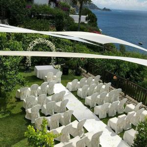 a group of white chairs in a field with the ocean at Hotel Costa Diva in Praiano