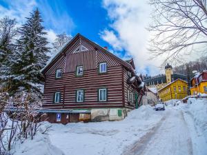 a large wooden house on a snow covered street at Penzion Zelené Údolí in Janske Lazne